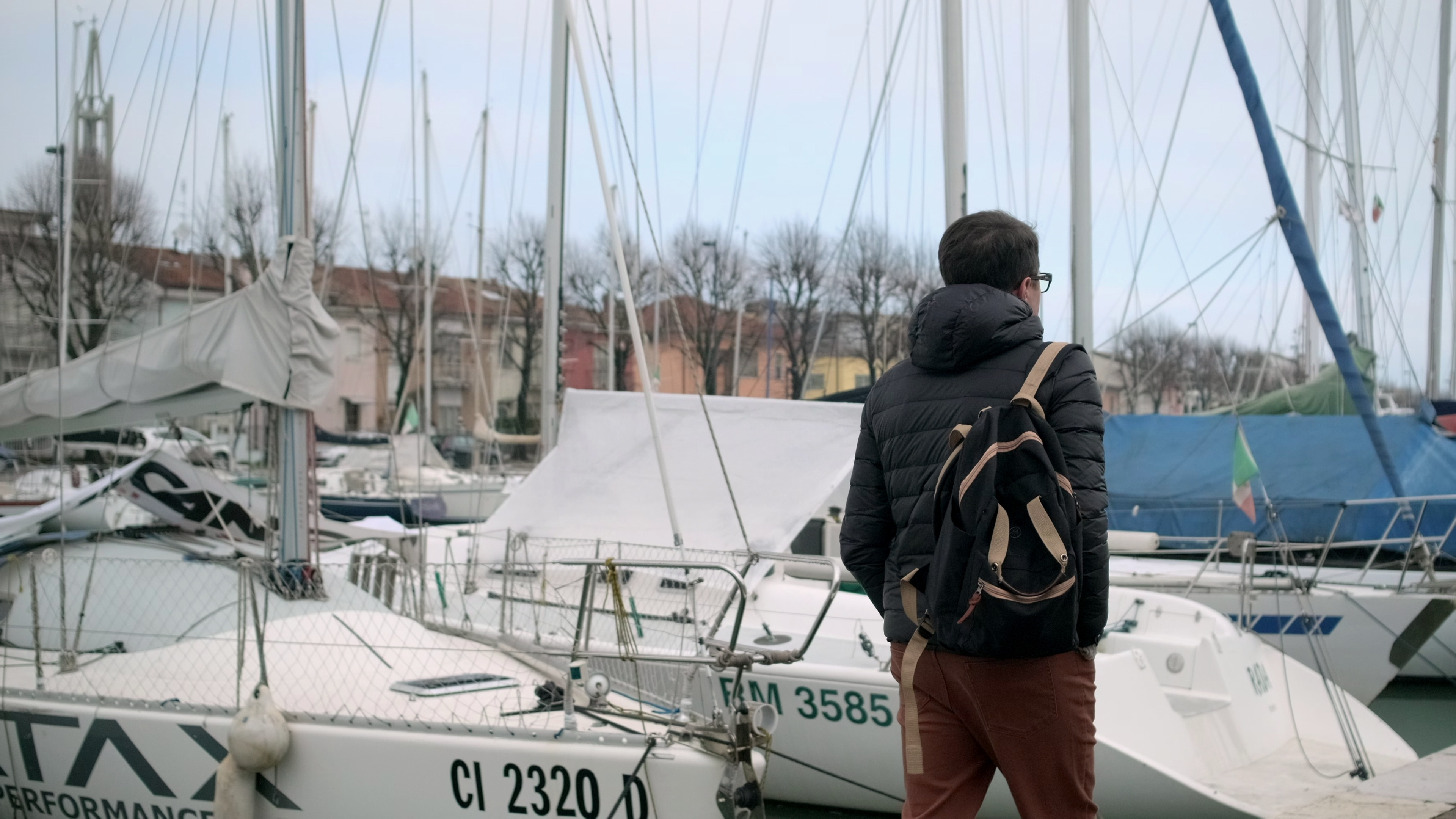 man-strolling-pensively-along-the-quay-with-boats-rimini-italy-SBI-349989874.jpg