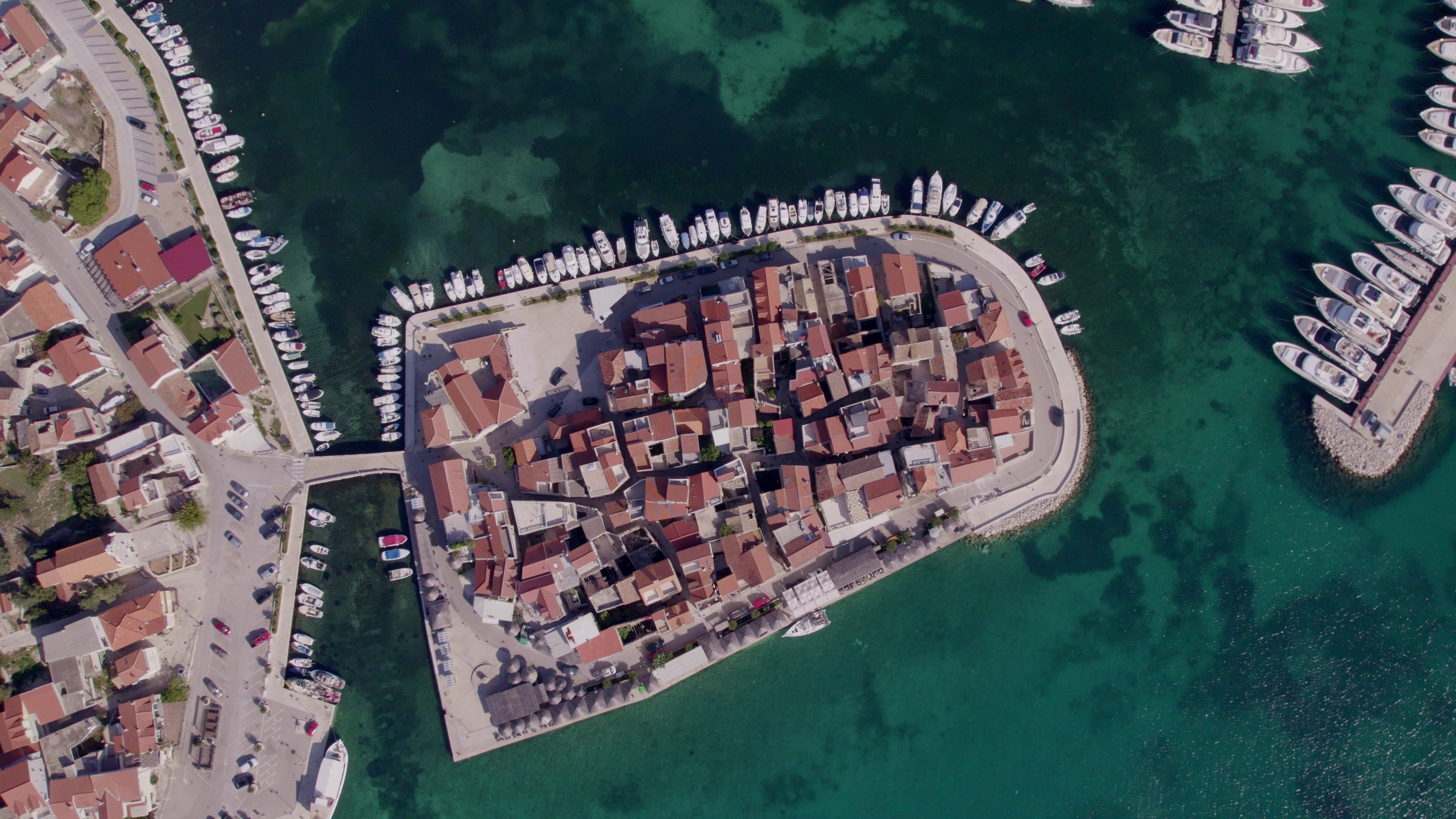 aerial-view-of-turquoise-sea-and-charming-town-with-boats-anchored-in-marina-tribunj-s-SBI-350936172.jpg